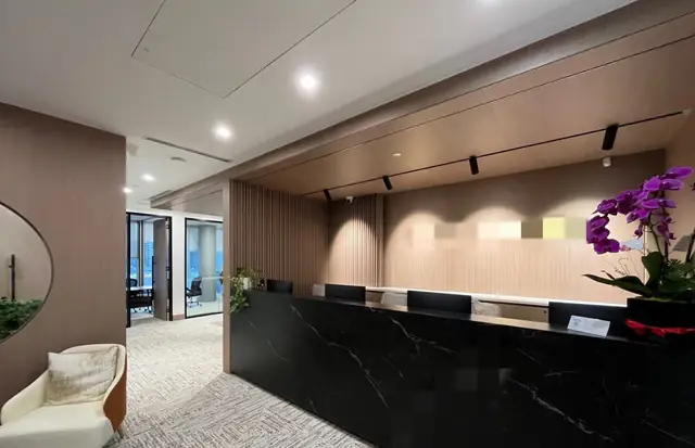 Corporate reception with a black stone desk and wood veneer wall panels