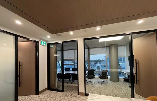 Glass-door boardroom entrance framed in wood veneer millwork