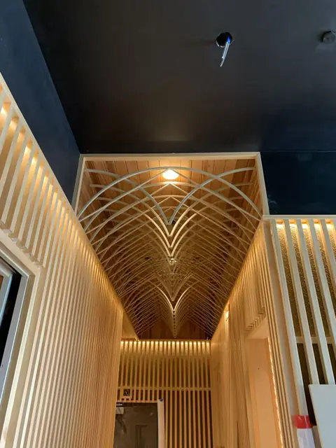 Backlit timber slat corridor with an arched lattice ceiling