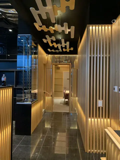 Restaurant entrance with backlit wood slats and a sculptural gold ceiling