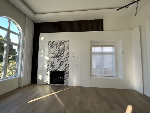 Flat-panel feature wall with a marble fireplace, fluted accent and window seat