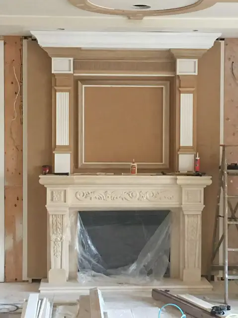 Classical fireplace surround with a raised-panel overmantel during installation