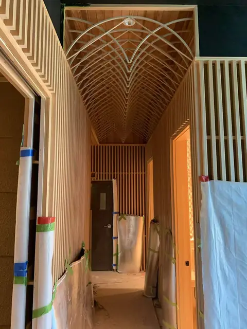 Timber slat corridor with arched lattice ceiling during installation