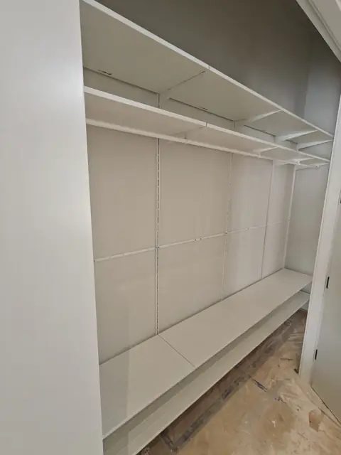 Built-in walk-in closet shelving with a storage bench