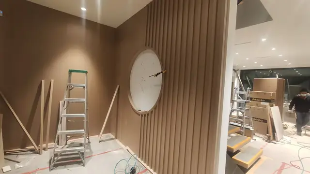 Wood slat feature wall with round mirror during installation